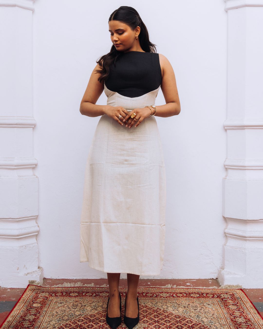 Mehvar dress Black on Ivory in Kala Cotton — Sukhanvar Sarmad SS2026. Woman wearing a black top and white skirt standing against a white wall.