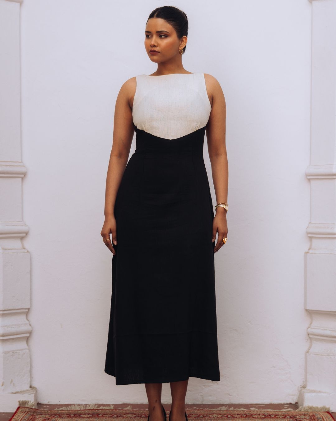 Woman wearing a black and white dress against a white wall. Sarmad Clothing collection by sukhanvar Mehvar Dress