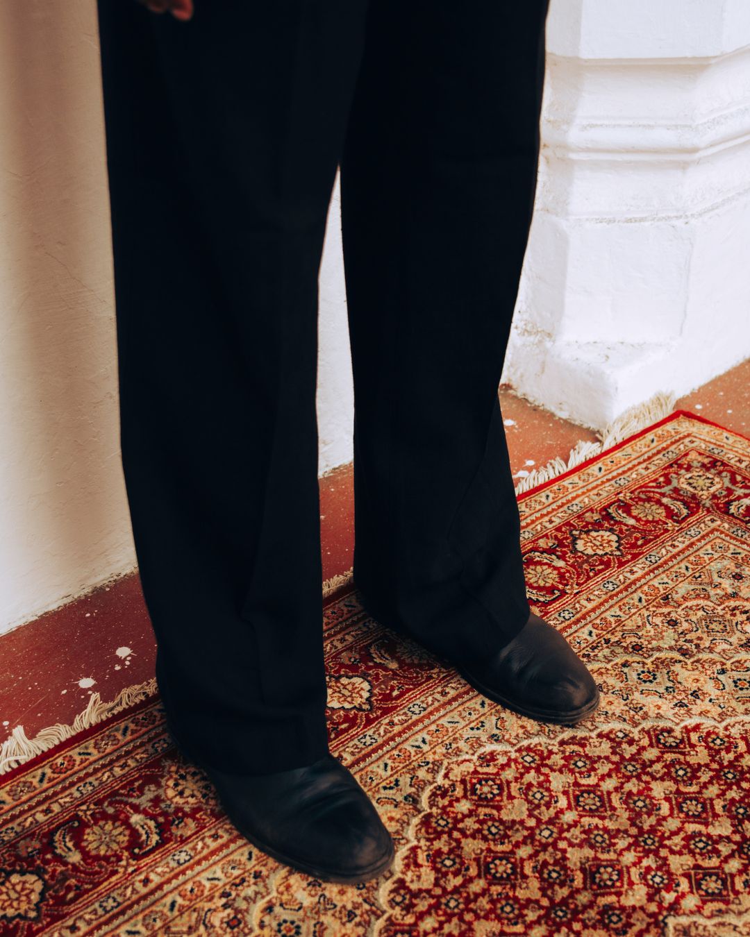 Person wearing black shoes and pants standing on a patterned rug. Sarmad Clothing collection by sukhanvar Mens Darwesh Co ord Set Shirt and wide leg pants Trouser Kala Cotton from kutch Bhujodi