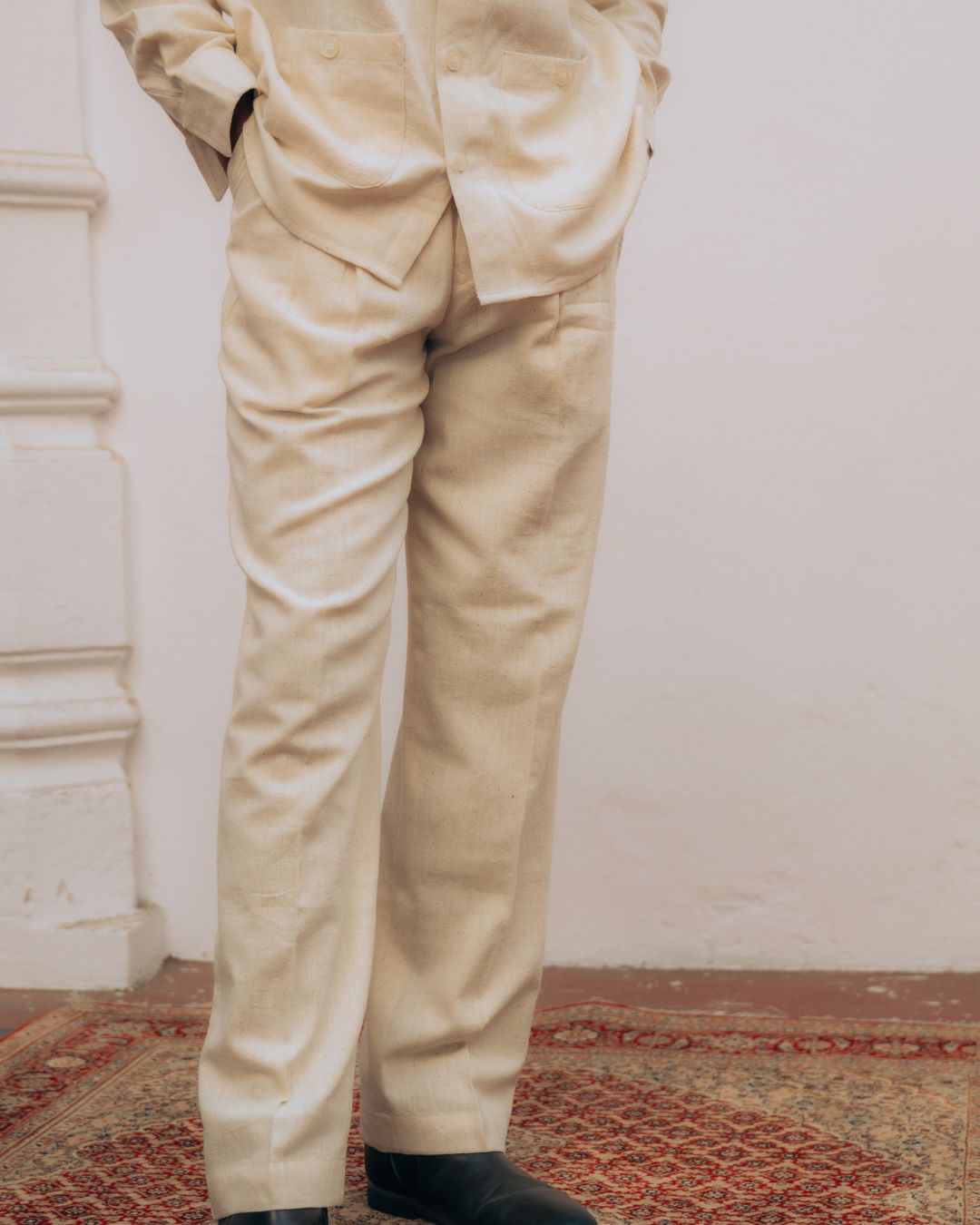 Beige pants worn by a person standing against a white wall. Sarmad Clothing collection by sukhanvar Mens Raavi Co ord Set 4 Pocket Shirt and Trouser Kala Cotton from kutch Bhujodi