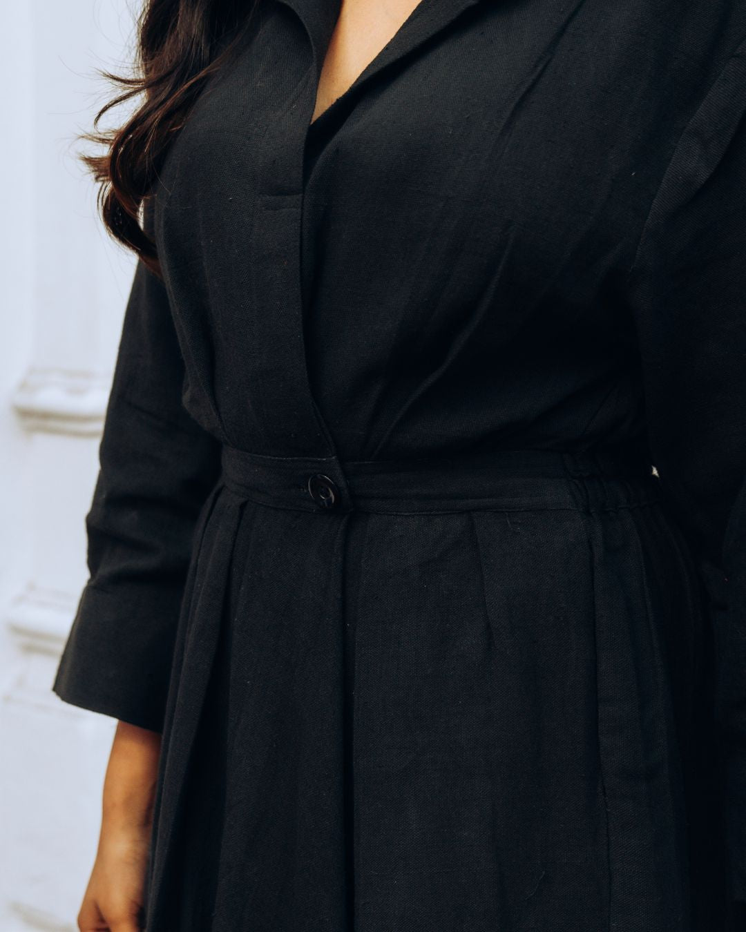 Black trench coat worn by a person with a blurred background Sarmad Clothing collection by sukhanvar Raqs Flowing Dress in KalaCotton from kutch Bhujodi