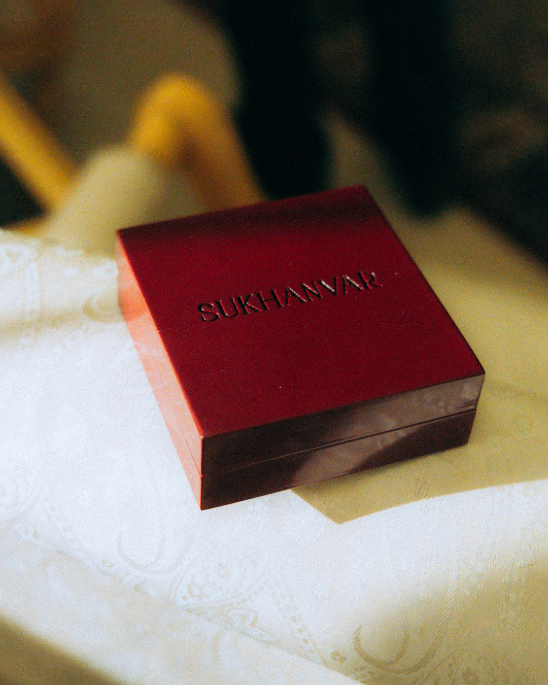 Sukhanvar Hijr attar oud perfume oil bottle with red tassel on dark wood shelf