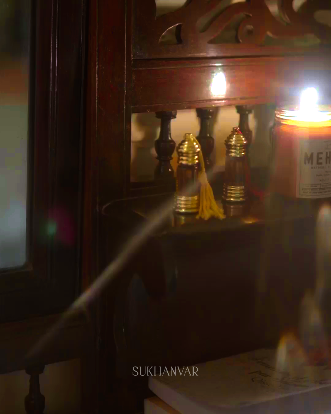 Sukhanvar Hijr Attar handcrafted small-batch perfume bottles displayed in a warm, atmospheric setting with a lit candle.