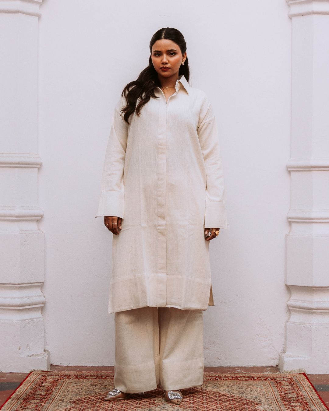 Woman wearing a white kurta with beige pants against a white wall. Sarmad Clothing collection by sukhanvar Mehr Co Ord Set Kurta Pant