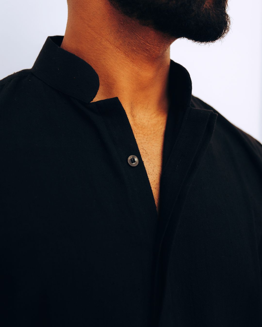 Close-up of a person wearing a black shirt with a button visible. Sarmad Clothing collection by sukhanvar Mens Darwesh Co ord Set Shirt and wide leg pants Trouser Kala Cotton from kutch Bhujodi